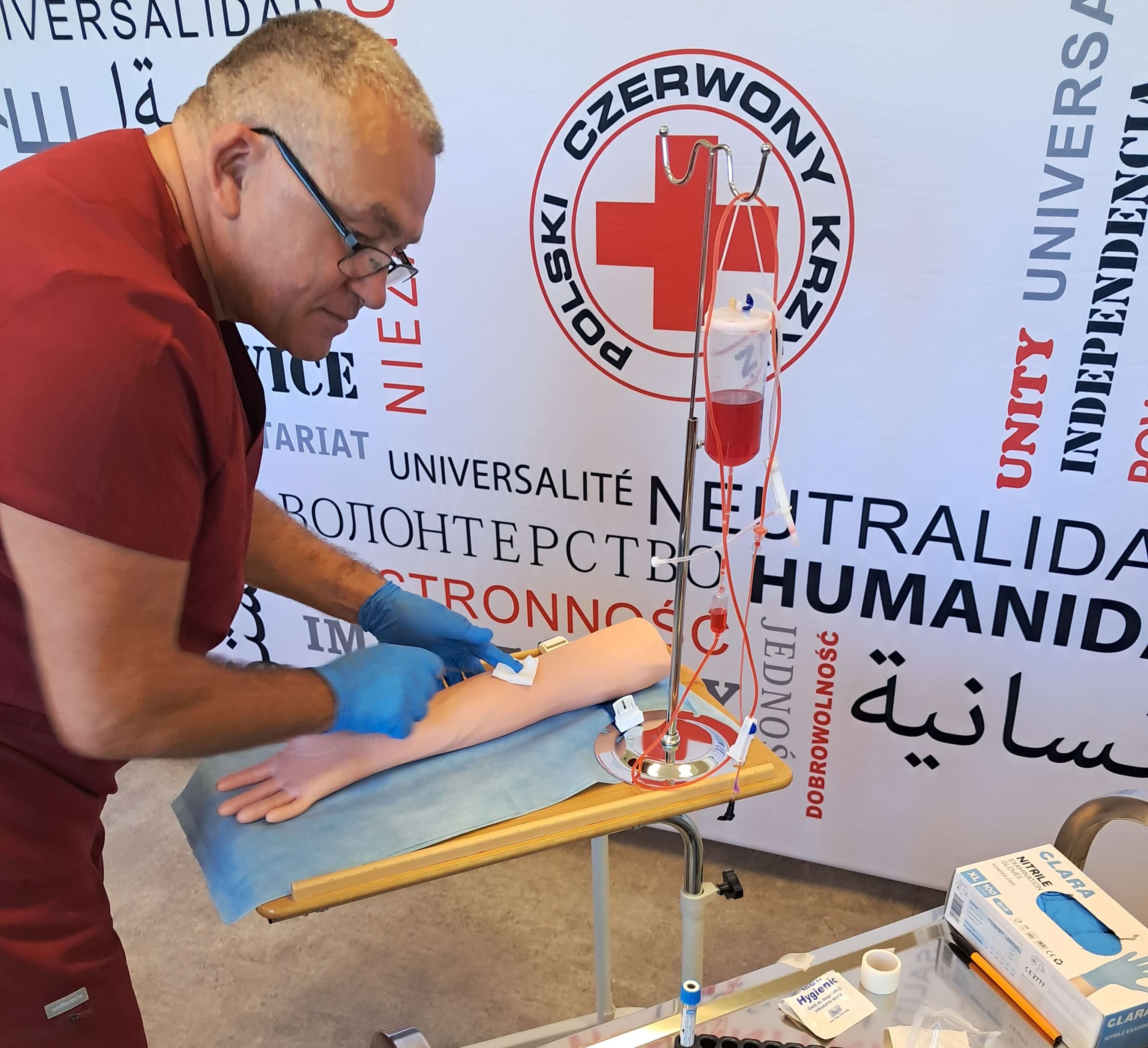 Opiekun medyczny pokazuje, jak prawidłowo pobierać krew na manekinie.